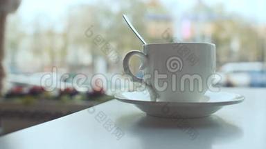 白色咖啡杯放在桌子上，咖啡放在背景窗上